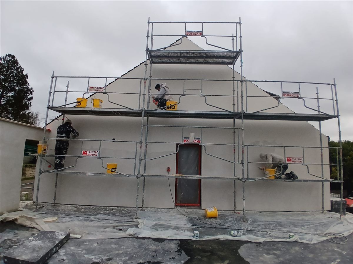 Application de l'enduit de façade sur une maison sous échafaudage