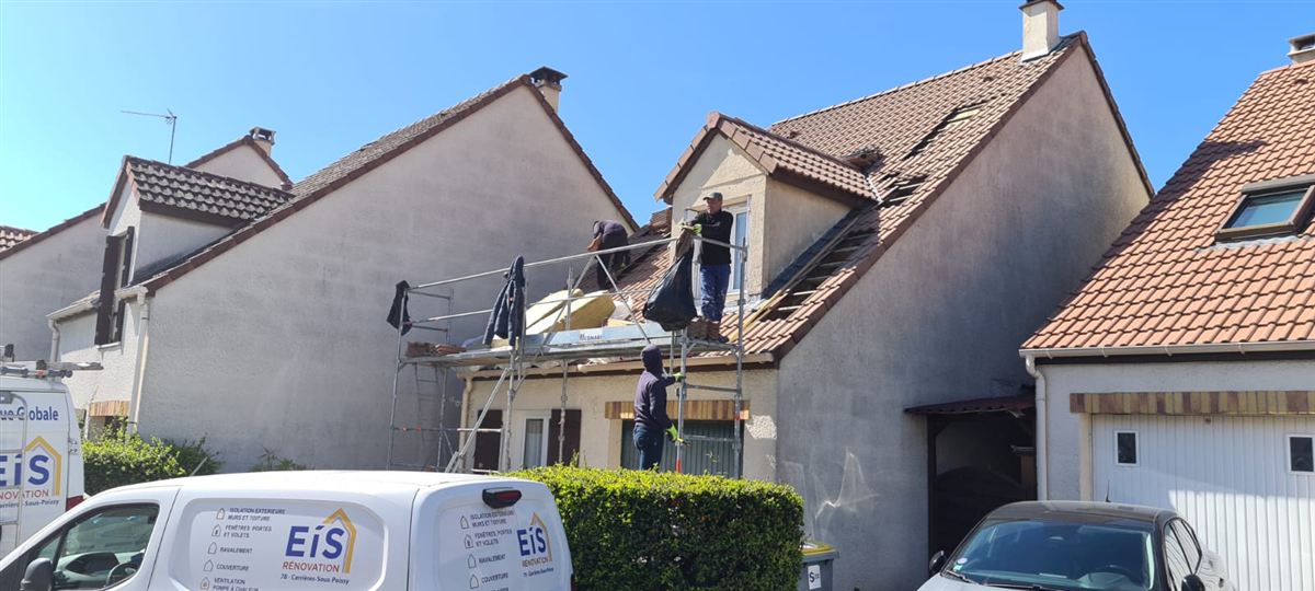 Couvreurs EIS au travail sur une toiture, la camionnette de l'entreprise devant la maison
