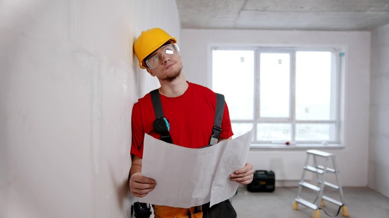Un homme en train de penser au travaux prioritaires de ravalement de de sa maison