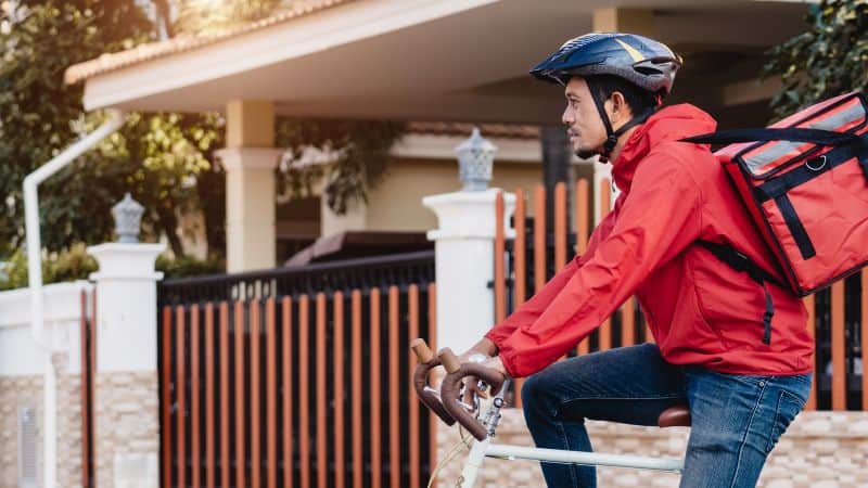 Un livreur à vélo devant un portail